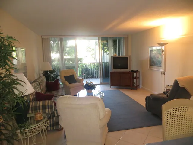 Spacious living room with large screen TV looking to the lanai and outdoors
