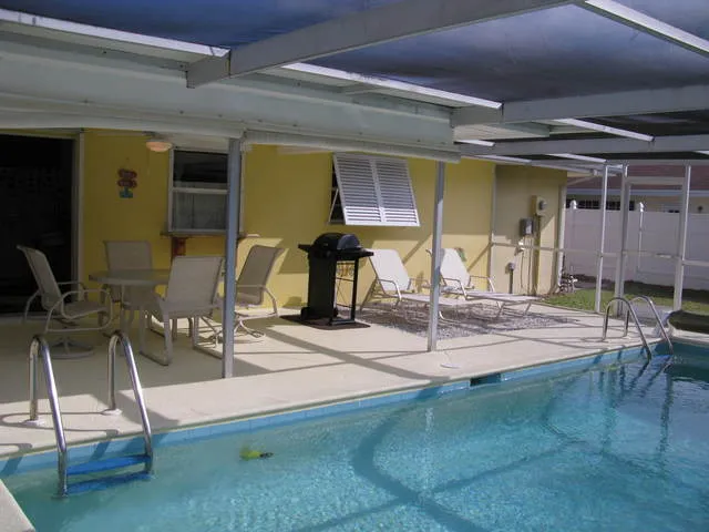 Lanai with seating, grill, lounge chairs, and pool