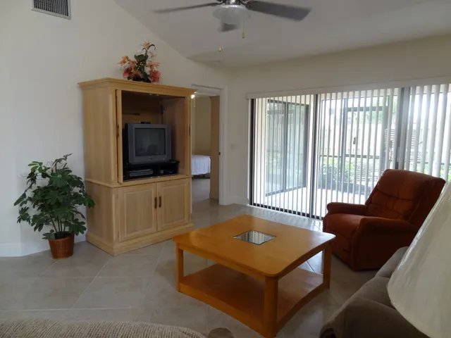 Living room with high ceilings comfy furnishings & triple sliders to lanai