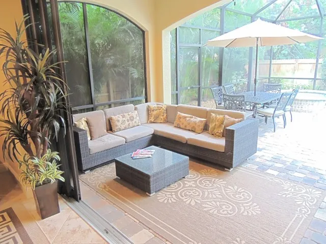 The outdoor living room has a sectional couch and flat screen tv