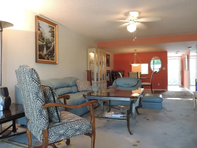 The living room features plenty of seating, tv, and opens to the lanai