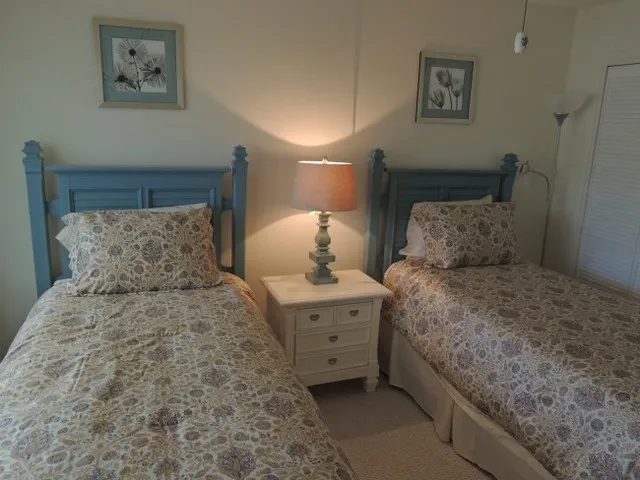 Guest bedroom features twin beds, closet, flat screen tv and a hall bath