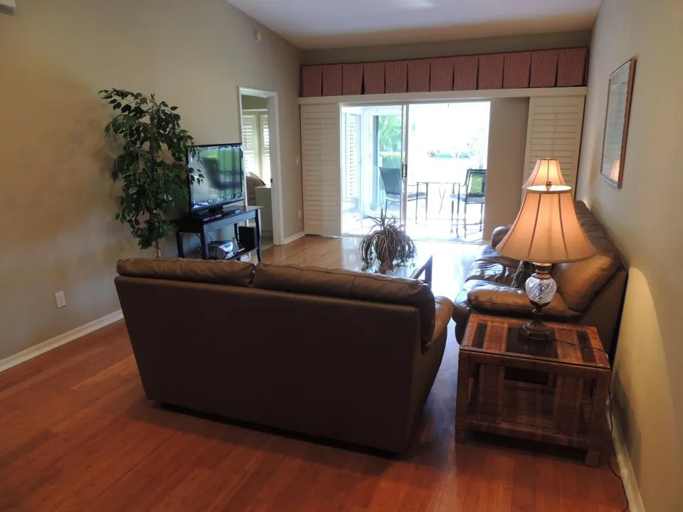 Living room features a flat screen tv, leather seating, & access to the lanai