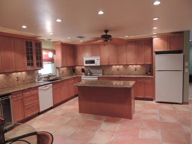 Renovated kitchen features an island, granite counter tops, wine chiller and comes fully equipped
