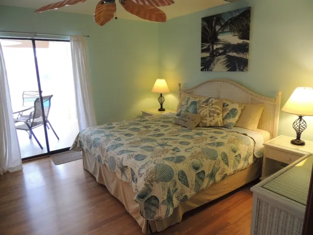 The master bedroom has a king bed, hardwood floors, & access to the pool area