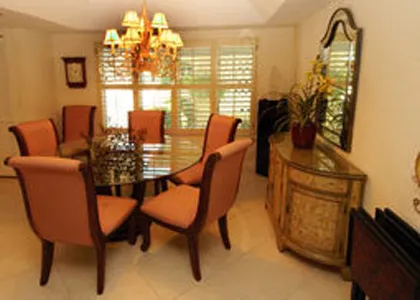 Glass top table dining in front of condo adjacent to kitchen access.