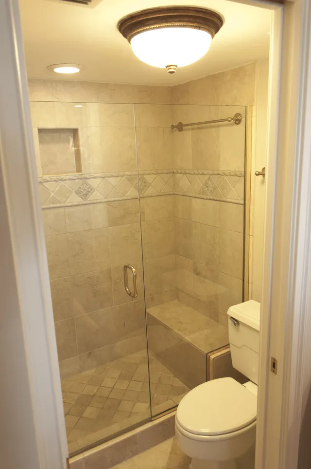 Tumbled marble and stone master bathroom shower with bench seat