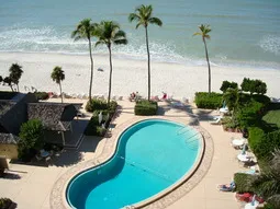sunny view of pool, deck chairs & grills from #807 lanai