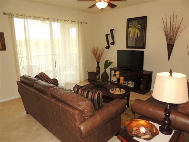 Living room features leather seating, flat screen tv and sliding glass doors to the lanai 